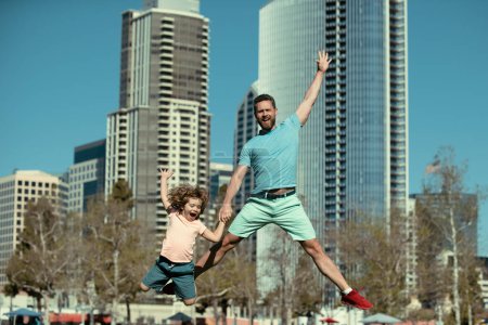 Foto de Emocionados padre e hijo saltando sobre el fondo urbano de la ciudad. Concepto de familia amigable - Imagen libre de derechos
