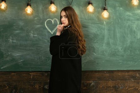 Photo for Teenager school - first love. School lessons. Young teenager with school books. Beautiful female holding her books in auditorium. Your text on Blackboard - Royalty Free Image