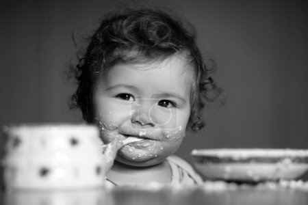 Photo for Cute little baby is being fed using spoon. Little child eating fruit puree indoors - Royalty Free Image