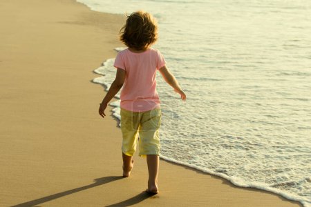 Foto de Los niños juegan con arena en la playa de verano. Niño feliz jugando en el mar. El chico se divierte al aire libre. Concepto vacaciones de verano - Imagen libre de derechos