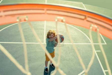 Foto de Ángulo de vista desde la parte superior de la pelota voladora a la cesta de baloncesto niño jugar - Imagen libre de derechos
