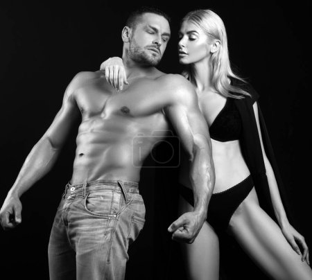 Téléchargez les photos : Homme masculin musclé posant avec sa femme sur fond noir. Fond noir - en image libre de droit