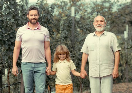 Téléchargez les photos : Trois générations d'hommes caucasiens. Enfant garçon avec père et vieux grand-père. Exploitations agricoles et jardinage à la ferme à la campagne - en image libre de droit