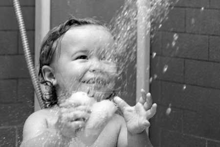 Foto de Bañarse sonriente bebé. Niño feliz con espuma de jabón en la cabeza. Divertido niño en la ducha - Imagen libre de derechos