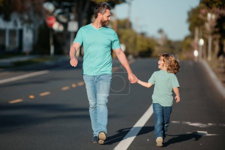 Téléchargez les photos : Père et fils se tenant la main passent du temps en plein air ensemble. Ville urbaine marcher famille - en image libre de droit