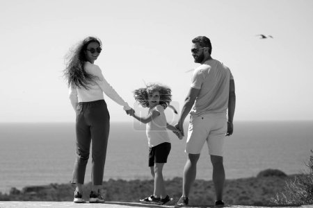 Téléchargez les photos : Famille sur la plage. Les gens s'amusent pendant les vacances d'été. Père, mère et enfant tenant la main contre la mer bleue. Concept de voyage vacances - en image libre de droit