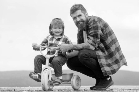 Photo for Father teaching his child son to ride a bicycle. Little boy learn to ride a bike with his daddy. Dad teaching son to ride bicycle. Fathers day - Royalty Free Image