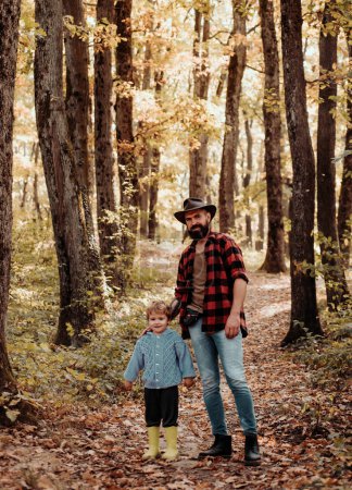 Foto de Familia feliz, padre e hijo pequeño jugando y riendo en el paseo de otoño. Padre e hijo caminando durante las actividades de senderismo en el bosque de otoño al atardecer
. - Imagen libre de derechos