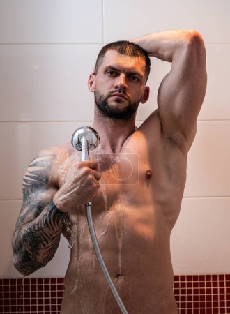 Photo for Skincare and bodycare. Young muscular man taking shower washing his body, back and shoulders. Handsome guy standing in the bathroom under hot water drops. Hygienic cleansing routine in bathroom - Royalty Free Image