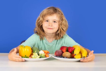 Photo for Fruits and vegetables for children. Healthy kids food. Closeup face of kid eating organic food, yogurt, milk. Child healthy eat. Smiling little boy eating food on kitchen - Royalty Free Image