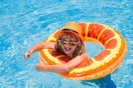 Photo for Child in sunglasses and summer hat floating in pool. Kids summer vacation. Children floating in water pool. Children playing and active leisure, swimming pool concept - Royalty Free Image