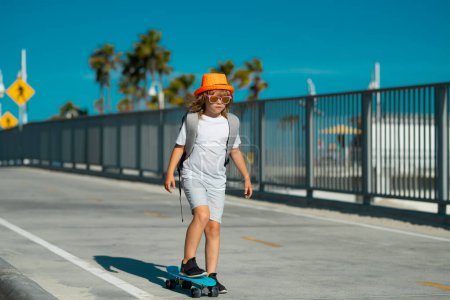 Téléchargez les photos : Garçon en skateboard. Enfant avec skateboard. Patins pour enfants. Sport et activité physique sains pour les écoliers en été. Plaisir sportif - en image libre de droit