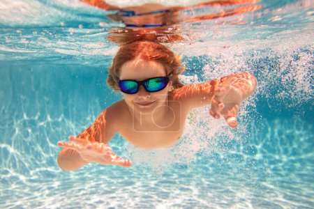 Téléchargez les photos : Enfant nageant dans la piscine sous l'eau. Enfant garçon nager sous l'eau dans la mer. Enfants jouant et plongeant dans la piscine. Les enfants drôles garçon jouent et nagent dans l'eau de mer ou de piscine. Concept vacances d'été - en image libre de droit