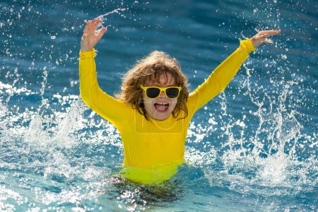 Téléchargez les photos : Éclaboussures d'enfants dans la piscine d'eau d'été. Un éclaboussure de gamin dans la piscine. Joyeux garçon heureux sautant dans la piscine, amusant de l'eau. Saut d'enfant dans la piscine et éclaboussures d'eau. éclaboussures d'enfants au bord de la piscine - en image libre de droit