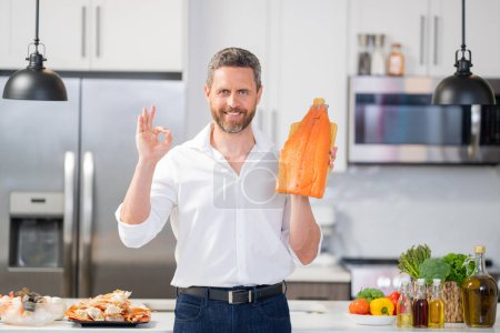 Photo for Portrait of cook man preparing fresh salmon at kitchen. Handsome chef man preparing raw fish salmon. Chef cooking seafood in kitchen. Millennial man hold raw fish salmon. Chef with salmon fillet - Royalty Free Image