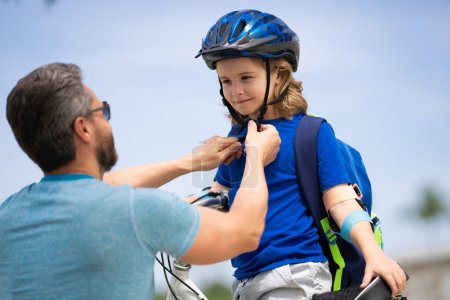 Photo for Father and son in bike helmet learning ride bicycle. Father helping his son to wear a cycling helmet. Child in safety helmet. Fathers day. Childhood and fatherhood. Child care - Royalty Free Image