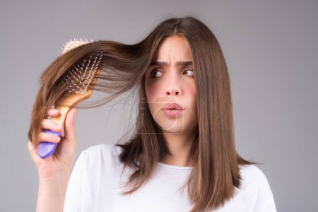 Téléchargez les photos : Jeune femme est très contrariée à cause de la perte de cheveux. Coupe de cheveux et soins capillaires sains. Problème sérieux de perte de cheveux pour le shampooing de soins de santé - en image libre de droit