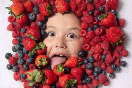 Photo for Kids face with close-up berry. Berries mix of strawberry, blueberry, raspberry, blackberry. Assorted mix of strawberry, blueberry, raspberry, blackberry with background near child face - Royalty Free Image