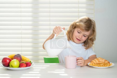 Photo for School chil pouring whole cows milk for breakfast. Schoolkid eating breakfast before school. Portrait of child sit at desk at home kitchen have delicious tasty nutritious breakfast - Royalty Free Image