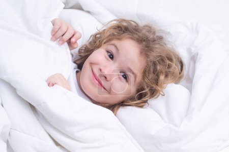Photo for Child enjoys sunny morning. Good time at home. Kid wakes up from sleep. Child wakes up in morning in bed. Morning awakening little child in bed - Royalty Free Image