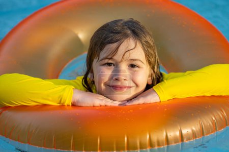 Photo for Happy young child enjoying summer vacation outdoors in water in the swimming pool. Cute little kid in swimming suit swim on an inflatable ring. Kid floating in a pool - Royalty Free Image