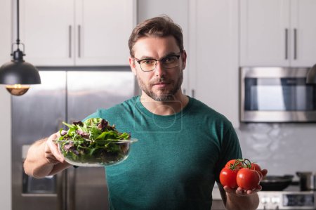 Photo for Portrait of attractive man preparing fresh natural weight loss meal at kitchen home indoors. Handsome cheerful man preparing meal in the kitchen. Healthy food, cooking concept - Royalty Free Image