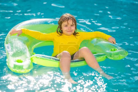 Téléchargez les photos : Amusant l'été. Petit enfant nageant dans la piscine. Enfant dans la piscine. Enfant se détendre nager sur anneau gonflable. Concept vacances d'été - en image libre de droit