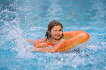 Téléchargez les photos : Enfants jouant dans la piscine. Heureux jeune enfant profitant de vacances d'été en plein air dans l'eau dans la piscine. Mignon petit enfant en maillot de bain nager sur un anneau gonflable. Enfant flottant dans une piscine - en image libre de droit