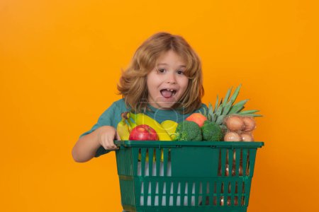 Téléchargez les photos : L'épicerie. Enfant excité au supermarché de légumes. Enfant avec panier. Enfant choisissant des aliments en magasin ou à l'épicerie - en image libre de droit