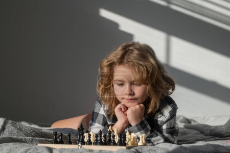 Photo for Cute boy are playing chess on bed at home. Kid thinking about chess. The concept of learning and growing children. Chess, success and winning. Board logic game, kids hobby and lifestyle - Royalty Free Image