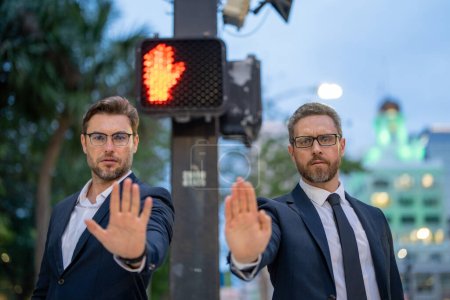 Photo for Businessmen doing stop sing with hand. Warning expression with negative and serious gesture. Stop hand gesture, businessman says hold on. Business man holding out hand, indicating stop on street - Royalty Free Image