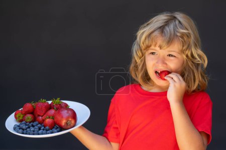 Photo for Close up summer portrait of kid with plate of mix summer fruits. Healthy organic strawberry fruit, summer season. Kid eating ripe strawberry - Royalty Free Image