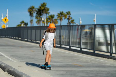 Photo for Kid on skateboard skating. Happy active child boy learning to balance on skateboard playing on the street. Riding and looks happy. Child playing surf skate or skateboard outdoor - Royalty Free Image
