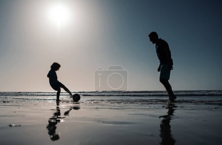 Foto de Padre e hijo juegan fútbol o fútbol en la playa en vacaciones familiares de verano - Imagen libre de derechos