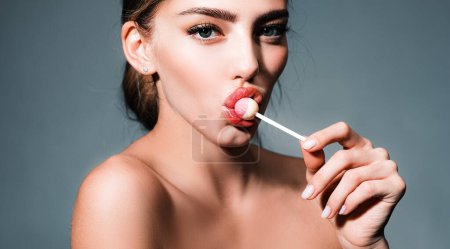 Photo for Woman with red lips licking lollipop. Beautiful young woman with clean fresh skin. Sensual woman. High fashion look. Gorgeous female sucks sweets. Beauty fashion portrait - Royalty Free Image