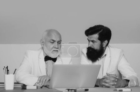 Photo for Coworking concept. Two businessman working at workplace. Businessmen using laptop at work. Old young generation discussion - Royalty Free Image