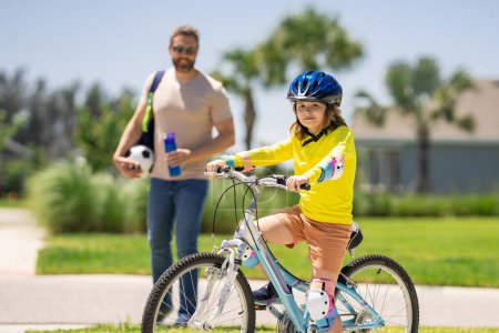 Fathers day. Boy learning to ride a bicycle with his father in park. Father teaching his son cycling on bike. Father learn little son to ride a bicycle. Father support child. Fathers day background