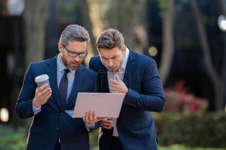 Photo for Business men team using laptop outdoor. Colleagues in suit talking outdoor. Businessmen discussing outdoor. Two business people talk project strategy. American businessmen in suits discuss business - Royalty Free Image