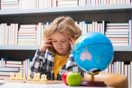 Foto de Inteligente niño concentrado y pensando jugando al ajedrez. Juegos Desarrollo cerebral para niños y lógica juego - Imagen libre de derechos