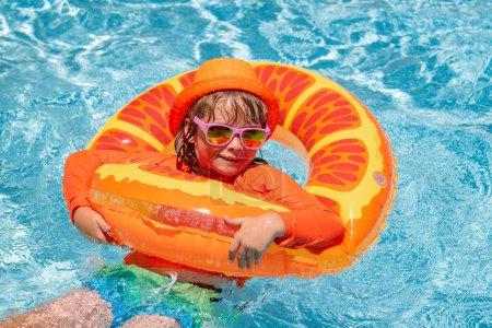 Foto de Niño en piscina en anillo inflable. Los niños nadan con flotador naranja. Juguete acuático, actividad deportiva al aire libre saludable para niños. Niños playa diversión - Imagen libre de derechos