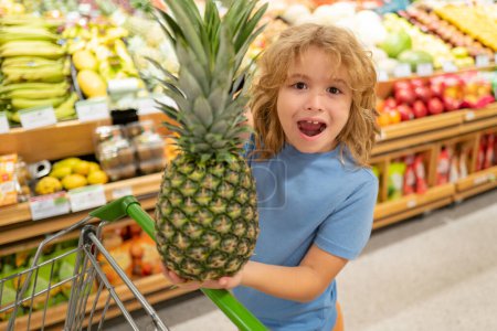 Photo for Portrait of child with shopping cart full of fresh vegetables in a food store. Supermarket shopping and grocery shop concept. Shopping kids. Child buying grocery in supermarket. hold shopping basket - Royalty Free Image