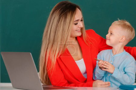 Photo for Mother and son together using computer laptop. School child learning education online lesson. Teacher helps school kids to learn lesson - Royalty Free Image