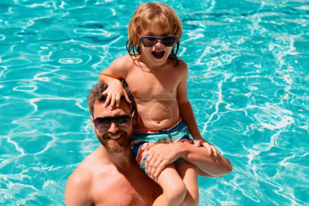 Téléchargez les photos : Père et fils nagent dans la piscine, famille d'été. Enfant avec papa jouant dans la piscine. Famille dans la piscine. Vacances d'été. Fête piscine - en image libre de droit