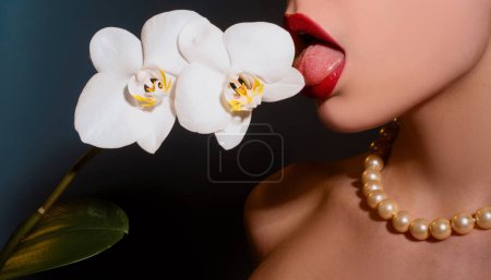Foto de Orquídea y labios de mujer. Flor de orquídea en boca de mujer sensual. Sexy mujer lengua lamer flor - Imagen libre de derechos
