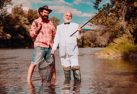 Photo for Senior fisherman in suit and bearded casual man fishing with fishing rod - Royalty Free Image