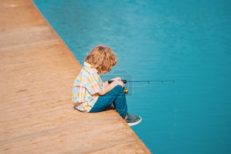Téléchargez les photos : Enfant garçon engagé dans des passe-temps de pêche, tient une canne à pêche. Mode de vie des enfants d'été. Pêche pour enfants le week-end, espace de copie - en image libre de droit