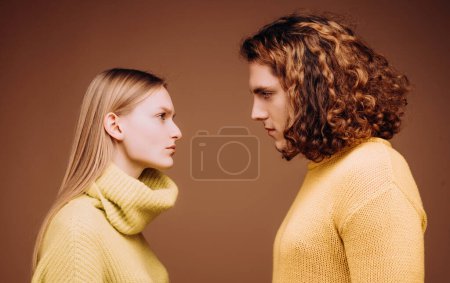 Photo for Side view. Curly man and blonde woman facing each other, eyes open. Concept of confrontation in the family. A couple standing face to face with a piercing look. Boyfriend and girlfriend hating each - Royalty Free Image