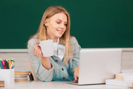Foto de Estudiante universitaria bebiendo café o té, trabajando en una computadora portátil en el aula, preparándose para un examen - Imagen libre de derechos