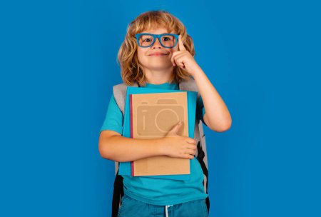 Photo for Schoolboy with backpack bag hold book. School children on isolated studio background. Thinking pensive kids, thoughtful emotions of school child, clever smart funny nerd have idea - Royalty Free Image