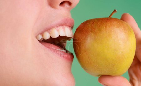 Téléchargez les photos : Belle jeune femme mangeant une pomme. Dents blanches saines ferment avec une pomme - en image libre de droit